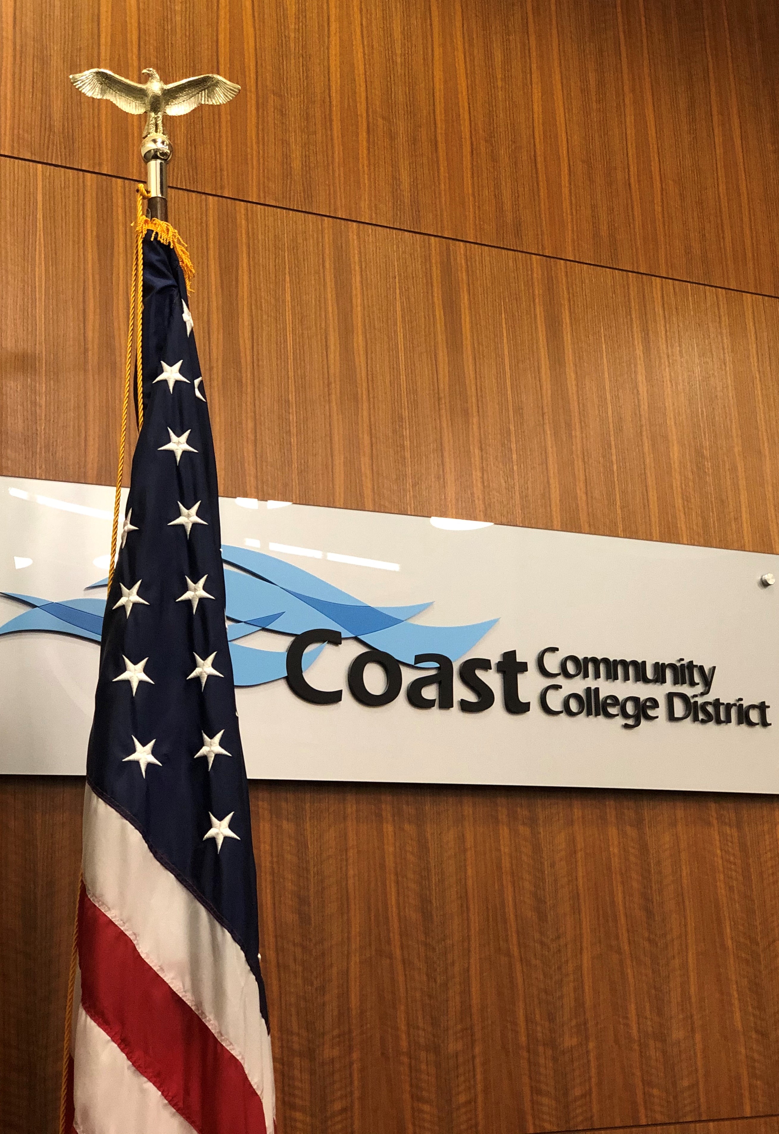 American Flag in front of the sign for Coast Community College District